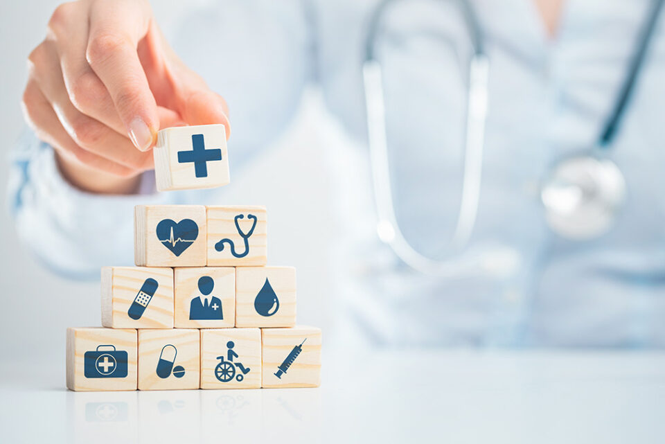 Someone stacking icon blocks on the table. They have symbols of health/healthcare associated with them.