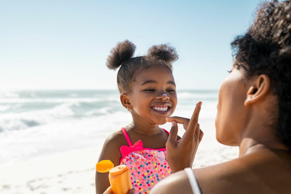 A caring mom putting sunscreen on her child at the beach