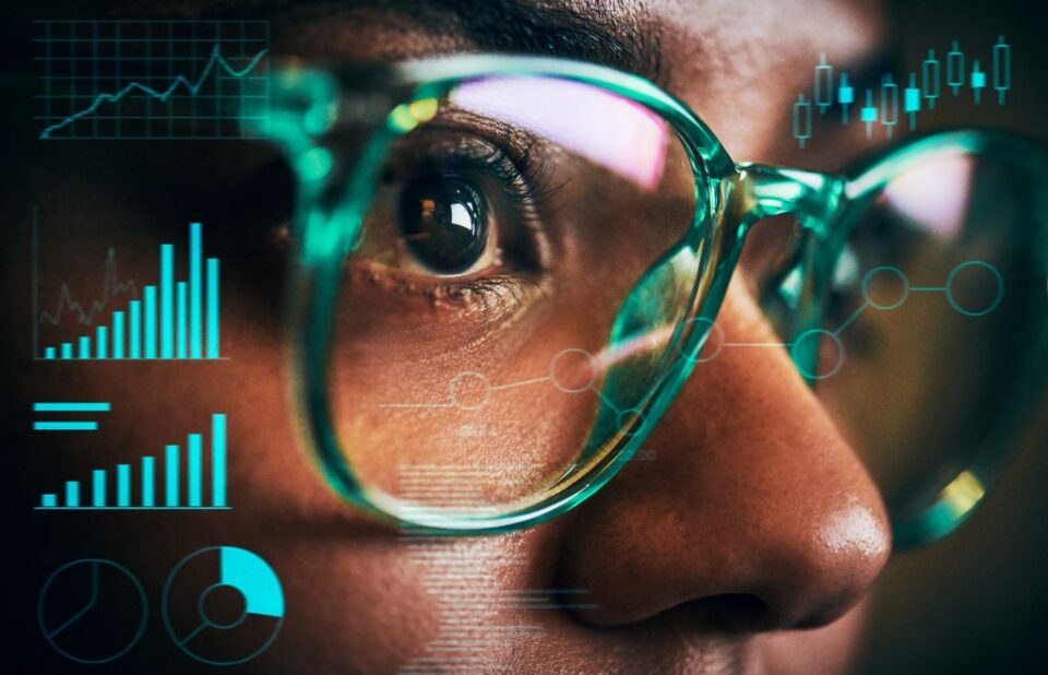 A person in teal glasses examines data and charts